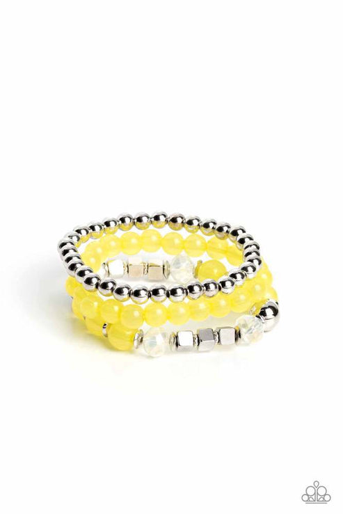 Varying in shape and size, shiny silver beads, silver cube beads, silver accents, primrose opaque beads, and reflective crystal-like beads are threaded along elastic stretchy bands, creating colorful layers across the wrist.  Sold as one set of three bracelets.