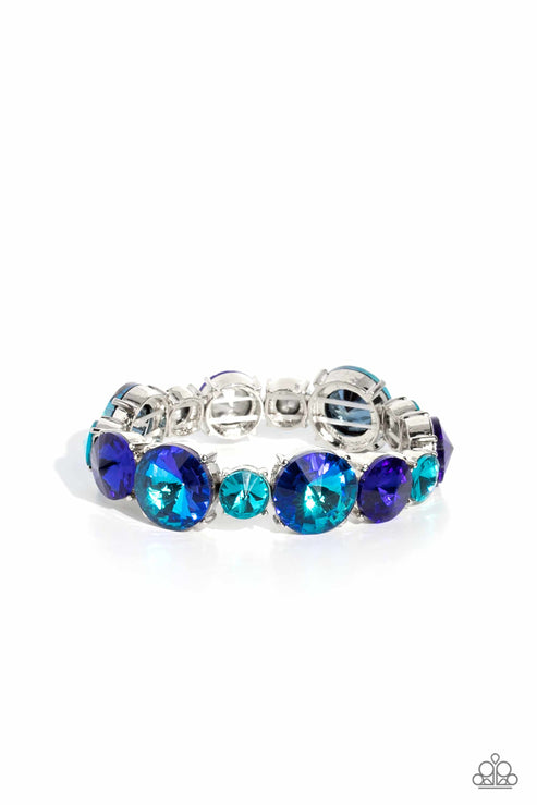 Pressed in silver-pronged frames, vibrant blue gems in varying sizes and shades alternate along stretchy bands around the wrist, creating a colorful pop of color. The larger blue gems feature a stellar UV shimmer for additional eye catching shimmer.  Sold as one individual bracelet.  Life Of The Party August 2023