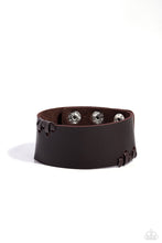 Sections of brown leathery laces are threaded along the edges of a thick brown leather band, resulting in an edgy display around the wrist.  Features an adjustable snap closure.   Sold as one individual bracelet