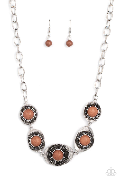 Earthy brown stones dot the centers of wavy irregular-shaped frames. Embellished with studded and etched feathery texture, the rustic frames create an earthy artisanal display below the collar. Features an adjustable clasp closure.  Sold as one individual necklace. Includes one pair of matching earrings.