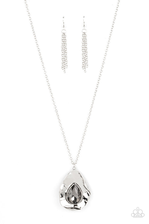 A warped silver frame gently folds around an oversized smoky teardrop gem center, resulting in a gritty yet glamorous pendant at the bottom of a lengthened silver chain. Features an adjustable clasp closure.  Sold as one individual necklace. Includes one pair of matching earrings.