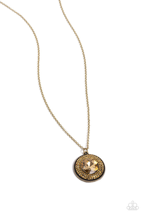 Sparkling with an oversized aurum center, a concaved brass disc encompassing radiating rows of shimmering aurum rhinestones cascades from an elongated brass chain, creating a striking impact. Features an adjustable clasp closure.  Sold as one individual necklace. Includes one pair of matching earrings.