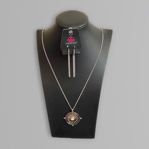 An iridescent multi rhinestone is pressed into the studded center of a compass inspired frame, creating a stellar pendant at the bottom of an extended silver chain. Due to its prismatic palette, color may vary. Features an adjustable clasp closure.  Sold as one individual necklace. Includes one pair of matching earrings.