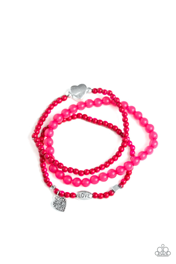 An array of glassy and polished pink beads are threaded along stretchy bands. Infused with silver accents, a collection of silver heart charms and a bead spelling out the word, 