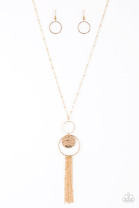 A delicately hammered gold disc is stamped in the inspirational word, "faith" and suspended from a double-hooped pendant at the bottom of an elongated gold satellite chain. A gold tassel swings from the bottom of the shimmery palette for a whimsical finish. Features an adjustable clasp closure.  Sold as one individual necklace. Includes one pair of matching earrings.