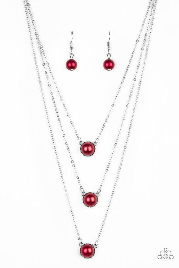 Three red pearl drop pendants layer down the chest in a refined fashion. Features an adjustable clasp closure.  Sold as one individual necklace. Includes one pair of matching earrings.