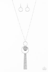 A delicately hammered silver disc is stamped in the inspirational word, "faith" and suspended from a double-hooped pendant at the bottom of an elongated silver satellite chain. A silver tassel swings from the bottom of the shimmery palette for a whimsical finish. Features an adjustable clasp closure.  Sold as one individual necklace. Includes one pair of matching earrings.