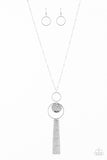 A delicately hammered silver disc is stamped in the inspirational word, "faith" and suspended from a double-hooped pendant at the bottom of an elongated silver satellite chain. A silver tassel swings from the bottom of the shimmery palette for a whimsical finish. Features an adjustable clasp closure.  Sold as one individual necklace. Includes one pair of matching earrings.