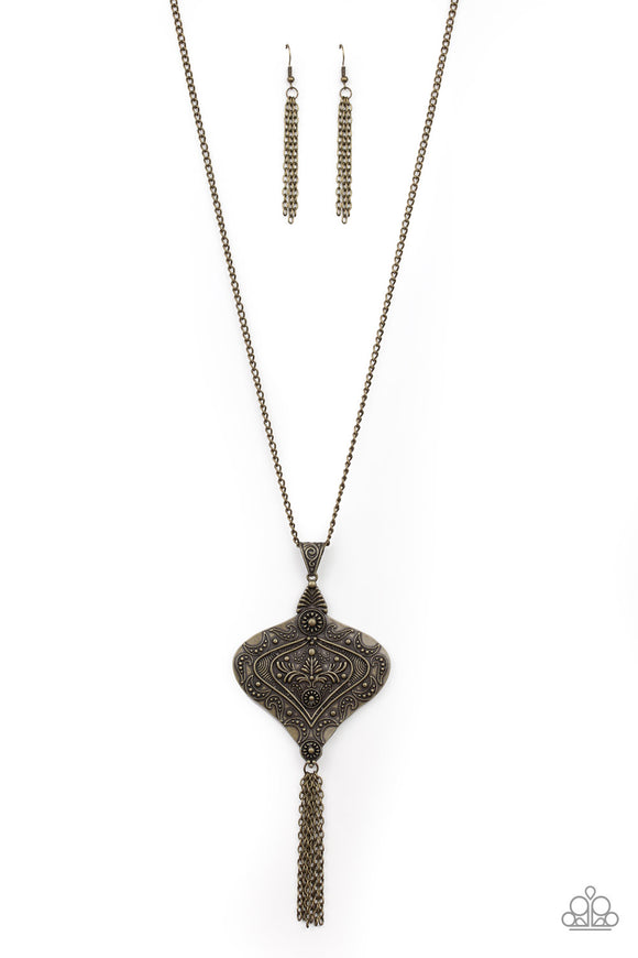 Embossed and studded in ornate details, an oversized brass pendant swings from the bottom of a lengthened brass chain for a rustic look. Antiqued brass chains stream from the bottom of the decorative frame, adding dramatic length to the seasonal piece. Features an adjustable clasp closure.  Sold as one individual necklace. Includes one pair of matching earrings.