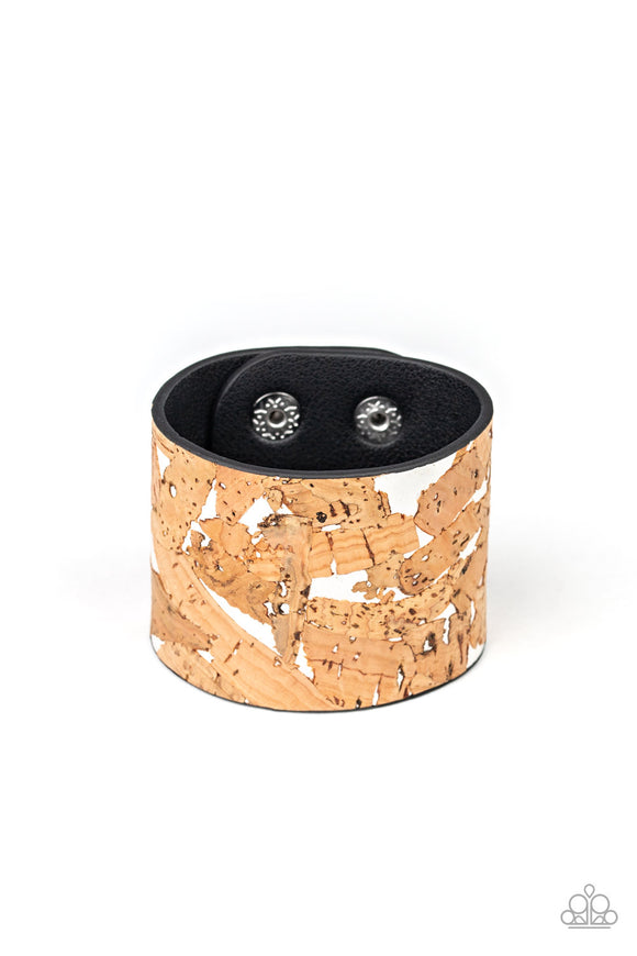 Pieces of cork have been plastered across the front of a shiny white leather band, creating an earthy look around the wrist. Features an adjustable snap closure.  Sold as one individual bracelet.