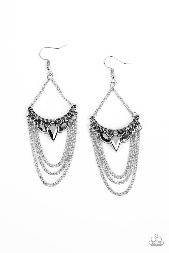 Tiers of shimmery silver chains swing from the bottom of a bowing silver frame encrusted in an array of smoky hematite rhinestones. Suspended by matching silver chains, the glittery frame coalesces into an edgy chandelier. Earring attaches to a standard fishhook fitting.  Sold as one pair of earrings.