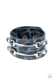 Two arcing silver bars are studded in place across the front of a thick leather band painted in blue and black cheetah print for a wild look. Features an adjustable snap closure.  Sold as one individual bracelet.