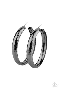 A thick piece of gunmetal has been heavily hammered and delicately curved into a dramatically handcrafted hoop. Earring attaches to a standard post fitting. Hoop measures approximately 2 ½” in diameter.  Sold as one pair of hoop earrings.