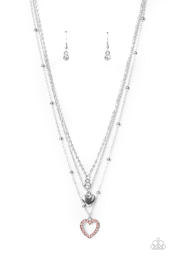 A dainty white rhinestone, shiny silver heart charm, and a pink rhinestone encrusted heart frame swings from the bottom of mismatched dainty silver chains, creating flirtatious layers below the collar. Features an adjustable clasp closure.  Sold as one individual necklace. Includes one pair of matching earrings.