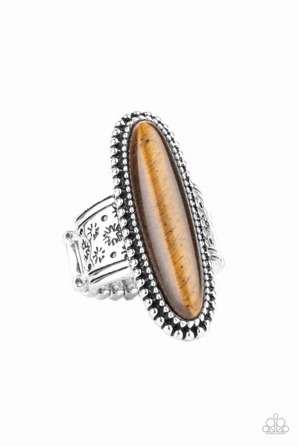 An oblong tiger's eye stone adorns the center of a studded silver frame that sits atop a thick silver band stamped in antiqued stars. Features a stretchy band for a flexible fit.  Sold as one individual ring.