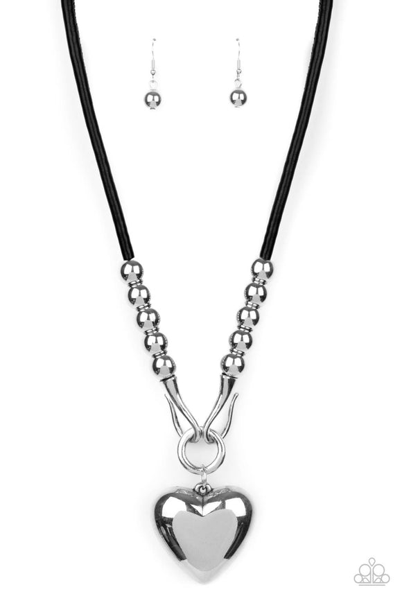 Featuring chunky silver beads, an oversized silver heart pendant swings from dramatic silver hook-like fittings that attach to a bold leather cord draped across the chest for a haute heartbreaker look. Features an adjustable clasp closure.  Sold as one individual necklace. Includes one pair of matching earrings.