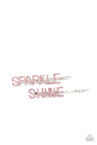 Glassy pink rhinestones spell out "Sparkle," and "Shine," across the fronts of two silver bobby pins, creating a sparkly duo.  Sold as one pair of decorative bobby pins.