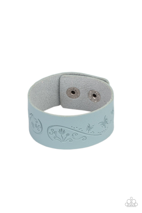 The front of a Cerulean leather band is stamped in a decorative butterfly and flower pattern, creating a whimsical display around the wrist. Features an adjustable snap closure.  Sold as one individual bracelet.