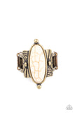 An oval white stone is nestled inside a studded brass fitting that sits atop a decorative brass frame stamped in tribal inspired textures, creating a rustic centerpiece. Features a stretchy band for a flexible fit.  Sold as one individual ring.