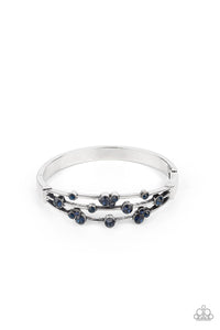 A smattering of glittery blue rhinestones adorn three silver bars that coalesce into a versatile silver cuff-like bangle around the wrist. Features a hinged closure.  Sold as one individual bracelet.