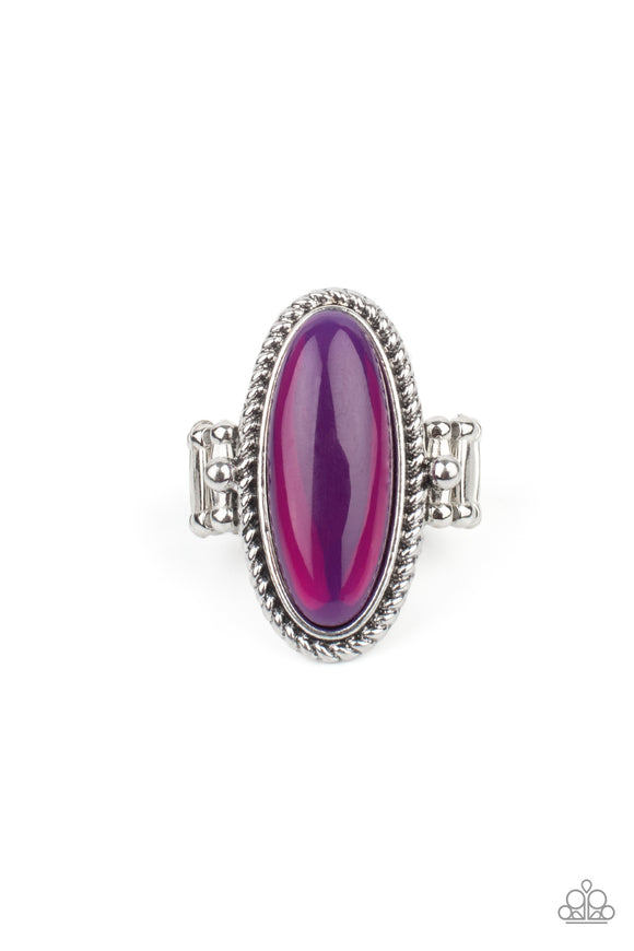 Featuring a glassy iridescence, an oval purple acrylic bead is pressed into the center of textured silver fittings, creating a mystical centerpiece atop the finger. Features a dainty stretchy band for a flexible fit.  Sold as one individual ring.