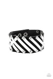 Pieces of white leather are studded in place across the front of a pieced together black leather band, creating edgy crisscrossed texture around the wrist. Features an adjustable snap closure.  Sold as one individual bracelet.