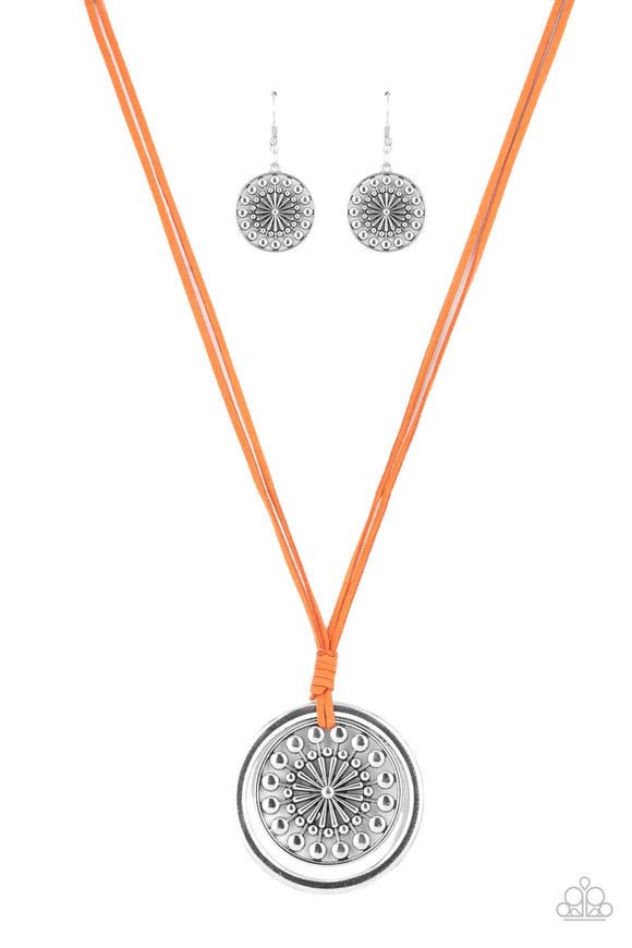 A lengthened piece of orange suede cording is knotted around a silver ring and decorative studded silver frame, creating a whimsy mandala-like pendant. Features an adjustable clasp closure.  Sold as one individual necklace. Includes one pair of matching earrings