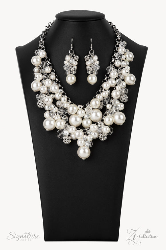 An elegantly effervescent collection of oversized pearls, glassy crystal-like beads, and white rhinestone studded silver ornaments effortlessly clusters along two bold silver chains below the collar. The bubbly bunched accents glamorously gather into a brilliantly boisterous fringe for an uproarious uptown fashion. Features an adjustable clasp closure.   Sold as one individual necklace. Includes one pair of matching earrings.   Named after the 2021 Seize the Spotlight winner, Janie V. The Janie