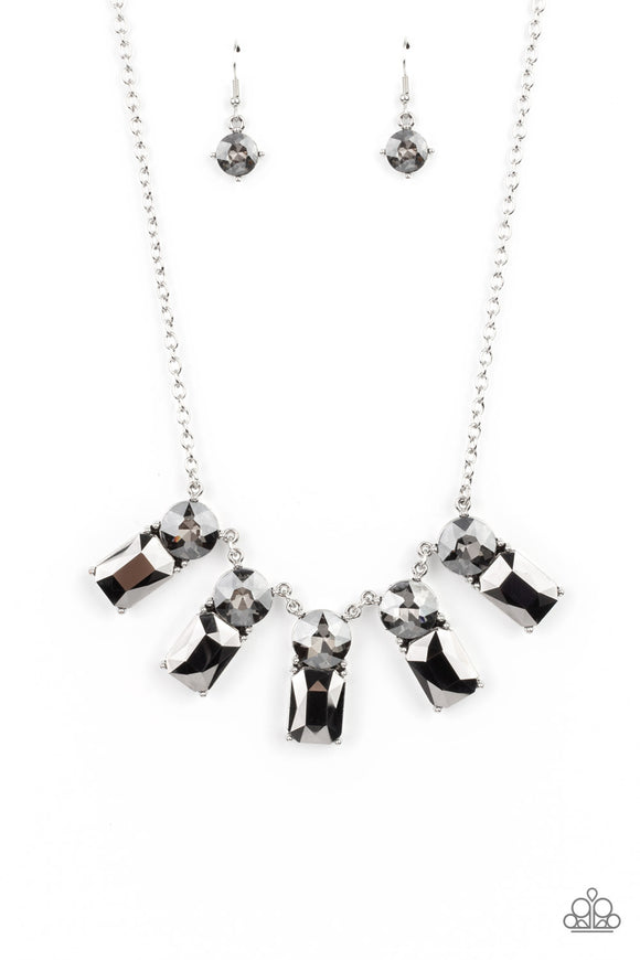 Featuring classic pronged fittings, a dramatic collection of oversized smoky rhinestones and emerald cut hematite gems fan out below the collar for an outrageous sparkle. Features an adjustable clasp closure.  Sold as one individual necklace. Includes one pair of matching earrings.