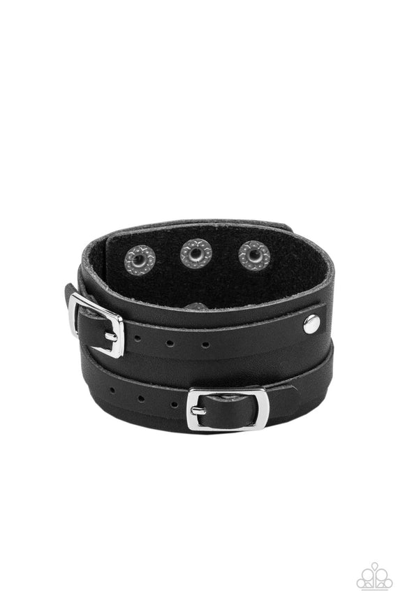 A pair of black leather buckles are buckled in place across the front of a rustic black leather band for a seasonal look. Features an adjustable snap closure.  Sold as one individual bracelet.