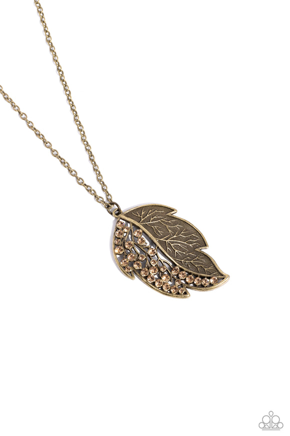 Half of a lifelike brass leaf frame is adorned in glittering topaz rhinestones as it hangs from the bottom of a lengthened brass chain, creating a simple seasonal sparkle. Features an adjustable clasp closure.  Sold as one individual necklace. Includes one pair of matching earrings.