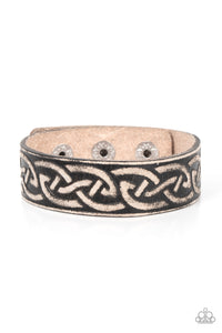 A black leather band is etched in a runic-like pattern, creating a rustic centerpiece around the wrist. Features an adjustable snap closure.  Sold as one individual bracelet.