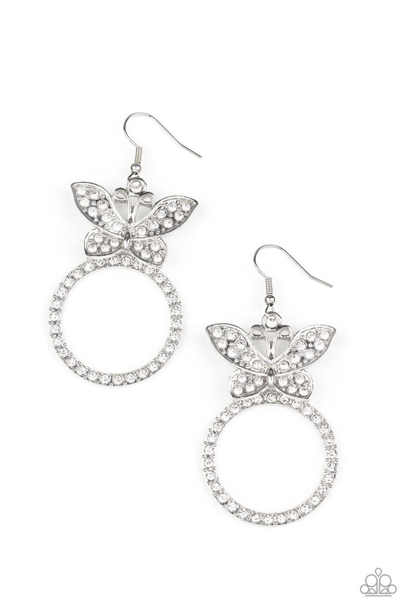 A white rhinestone encrusted silver butterfly flutters atop a silver ring dotted in matching white rhinestones, resulting in a dazzling statement piece. Earring attaches to a standard fishhook fitting.  Sold as one pair of earrings.