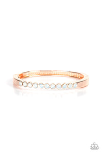 An opalescent row of white rhinestones hinges to a glistening rose gold bar that curves around the wrist, creating a sparkly cuff-like bracelet. Features a hinged closure.  Sold as one individual bracelet.