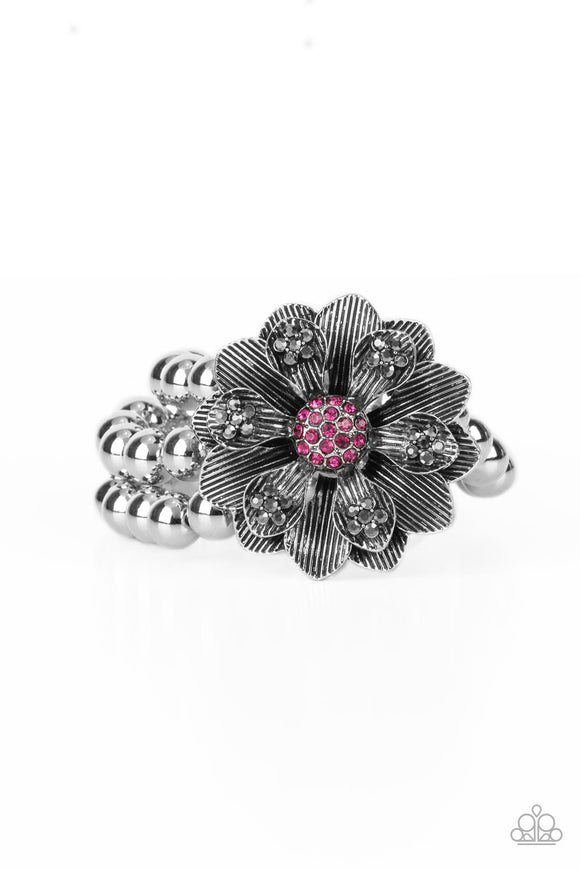 A daring oversized silver flower is composed of petals lined in antiqued silver and dotted with smoky hematite rhinestones. A sphere of dainty Fuchsia Fedora rhinestones creates the center of the flower as it sits atop a trio of shiny silver beaded stretchy bands around the wrist for a dramatically whimsical look.  Sold as one individual bracelet.