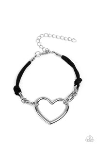 Strands of black suede knot around sections of chunky silver chains that have been adorned in an oversized silver heart frame, resulting in a flirtatious display around the wrist. Features an adjustable clasp closure.  Sold as one individual bracelet.