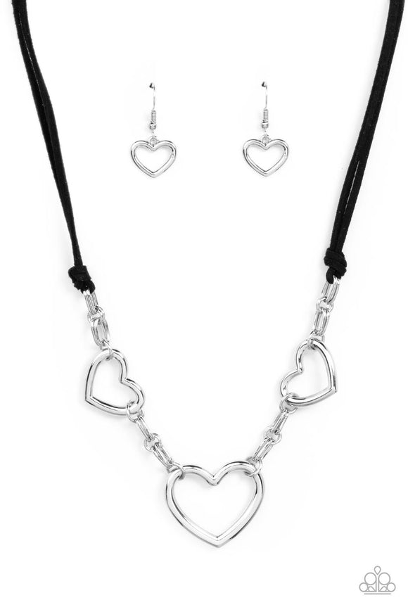 Strands of black suede knot around sections of chunky silver chains that have been adorned in oversized silver heart frames, resulting in a flirtatious display below the collar. Features an adjustable clasp closure.  Sold as one individual necklace. Includes one pair of matching earrings.