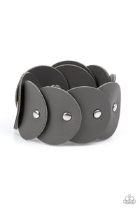 Overlapping gray leather discs are studded in place around the wrist, resulting in a dizzying rustic centerpiece. Features an adjustable snap closure.  Sold as one individual bracelet.