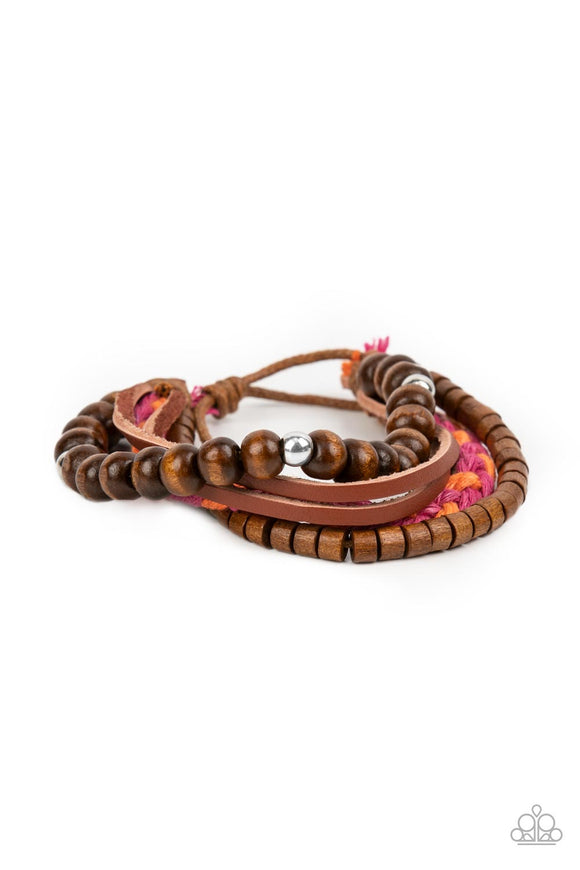 A braid of pink and orange twine-like cording joins strands of mismatched wooden beads and dainty leather bands around the wrist, layering into a colorfully earthy display. Features an adjustable sliding knot closure.  Sold as one individual bracelet.