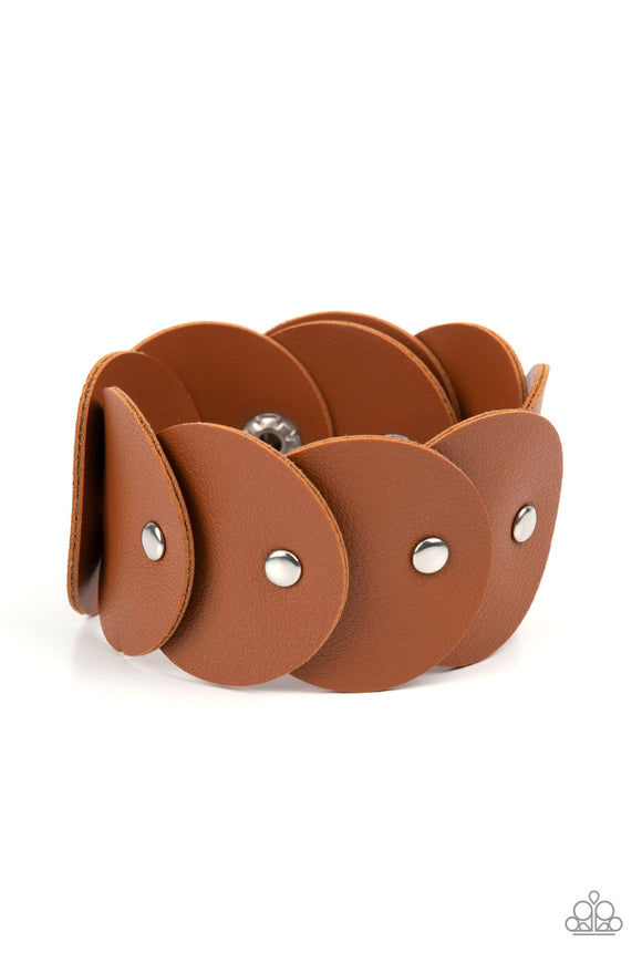 Overlapping tan leather discs are studded in place around the wrist, resulting in a dizzying rustic centerpiece. Features an adjustable snap closure.  Sold as one individual bracelet.