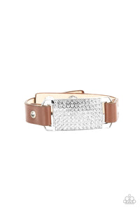 Brown leather bands are looped through the ends of a white rhinestone embellished silver frame and studded in place with glitzy white rhinestone studs, creating a glamorous centerpiece around the wrist. Features an adjustable snap closure.  Sold as one individual bracelet.