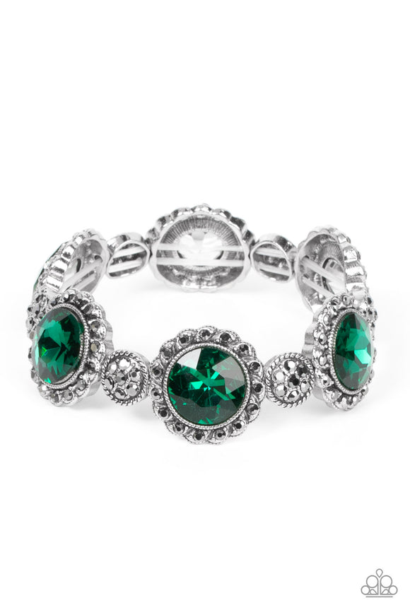 An oversized green rhinestone adorns the center of a hematite rhinestone petaled floral frame. Infused with hematite dotted silver accents, the glitzy floral frames sparkle along stretchy bands around the wrist for a glamorous finish.  Sold as one individual bracelet.