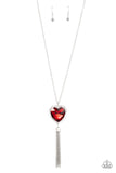 Bordered in a ribbon of glassy white rhinestones, an oversized red heart-shaped gem seemingly floats at the bottom of an extended silver chain. A shimmery silver chain tassel dances from the bottom of the sparkly pendant for a flirtatious finish. Features an adjustable clasp closure.  Sold as one individual necklace. Includes one pair of matching earrings.