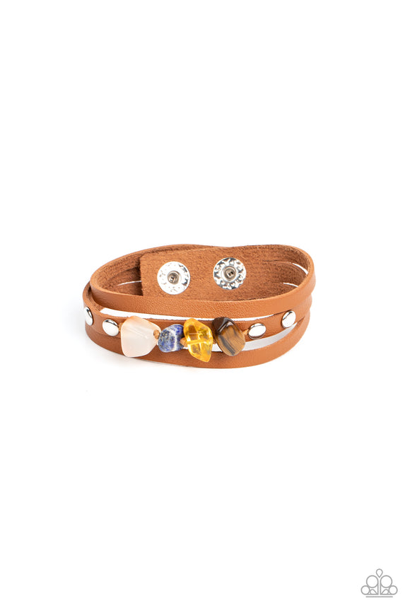 Chunks of tiger's eye, citrine, lapis lazuli and quartz stones are threaded along a knotted cord that is studded in place along the center band of a layered leather bracelet for a seasonal finish. Features an adjustable snap closure.  Sold as one individual bracelet.