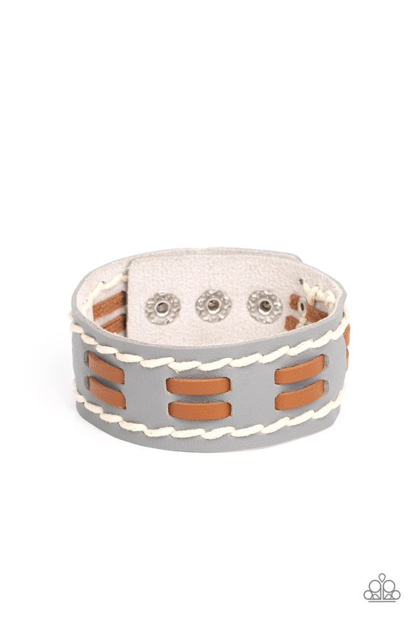 Flanked with two stitched rows, two rows of brown leather laces are threaded through the center of a gray leather band for a rustic pop of color around the wrist. Features an adjustable snap closure.  Sold as one individual bracelet.