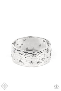 A wide silver band, hammered with subtle texture, is sprinkled with a constellation of embossed silver stars and sparkling dainty white rhinestones, creating a heavenly display around the wrist. Features a hinged closure.  Sold as one individual bracelet.