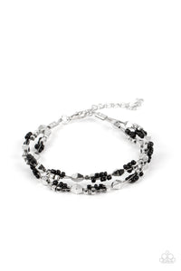 A dainty collection of faceted silver beads, black seed beads, and silver cubes are threaded along multiple strands of silver wire around the wrist, creating clustered layers. Features an adjustable clasp closure.  Sold as one individual bracelet.