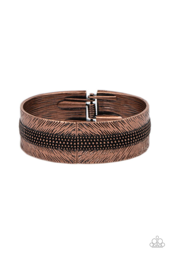A thick band of copper is etched in feathery texture, creating a tactile statement piece that boldly wraps around the wrist. Rows of antiqued copper studs travel around the center of the thick copper band, adding eye-catching dimension and grit to the design. Features a hinged closure.  Sold as one individual bracelet.