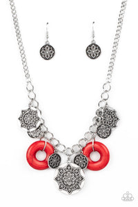 A collection of silver discs, embellished with intricate mandala-like designs, dances along a thick silver chain, with a pair of polished red stone rings adding a pop of color to the rustic design. Features an adjustable clasp closure.  Sold as one individual necklace. Includes one pair of matching earrings.