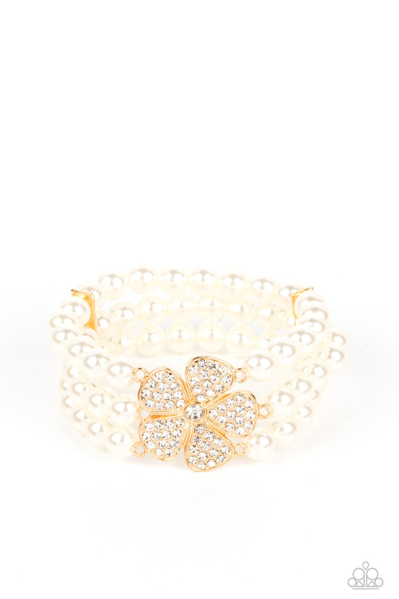 Separated by dainty gold plates, classic white pearls are threaded along three stretchy bands around the wrist. Encrusted in glassy white rhinestones, a glitzy gold flower blooms at the center of the wrist for a fierce floral statement.  Sold as one individual bracelet.